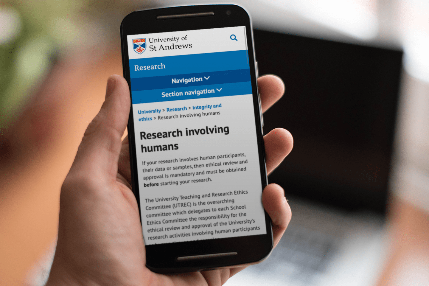 Hand holding mobile phone open to new "Research involving humans" section