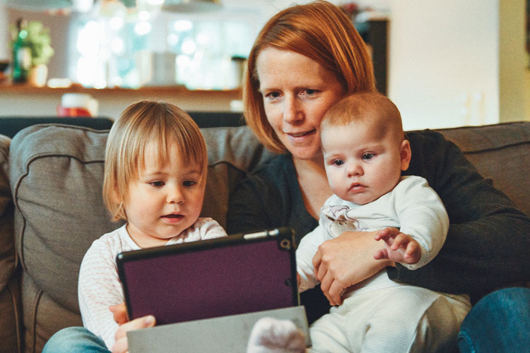 Woman holding children using a tablet device
